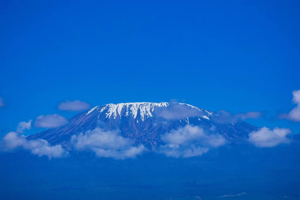 The snow-covered Kibo summit of Mount Kilimanjaro seen above clouds